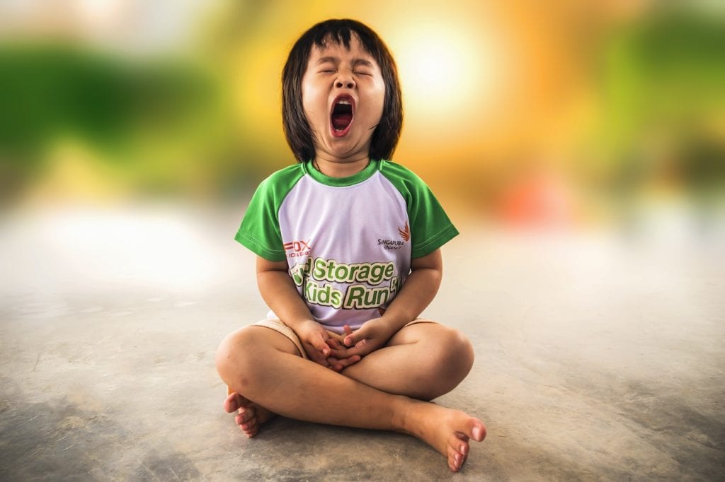 A child yawns in cross-legged position.