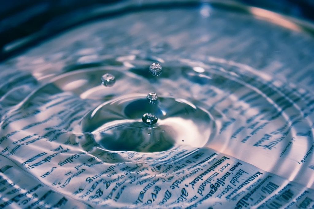 Drops of water create ripples on a book.