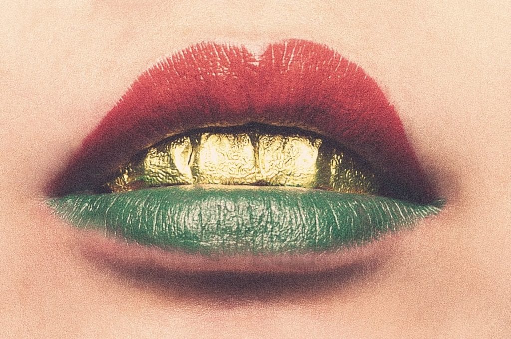 Lips painted with coloured lip balm, and golden teeth.