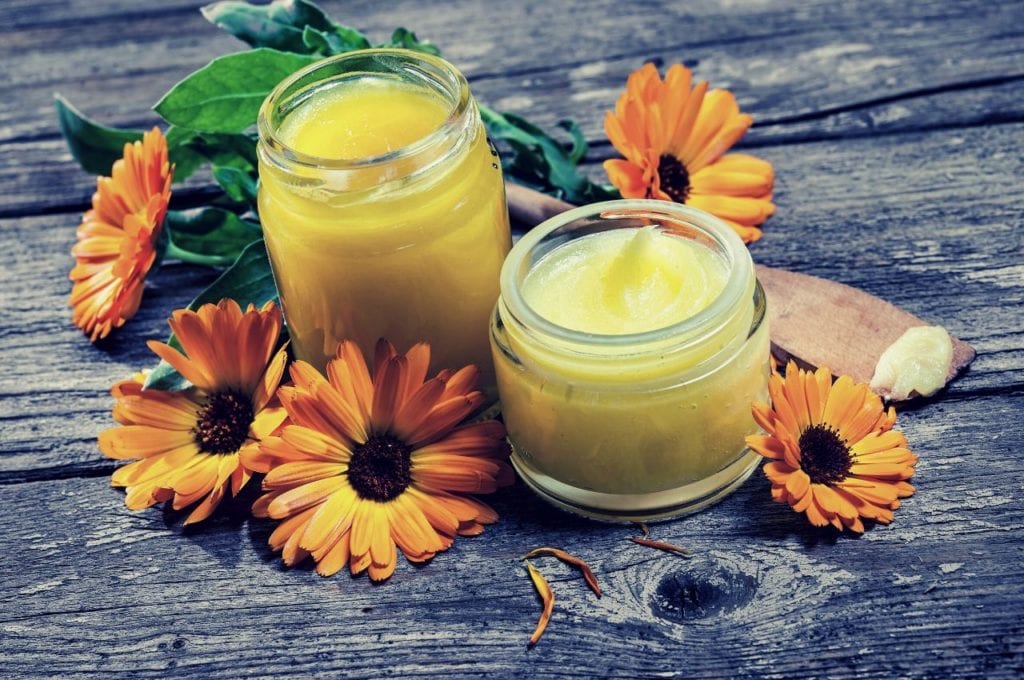 5 DIY CBD Isolate Products You Can Make At Home | Recipes | My Supply Co. A jar of herbal ointment arranged with flowers.