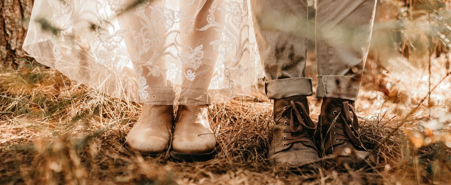 A pair of shoes of a couple standing beside each other.