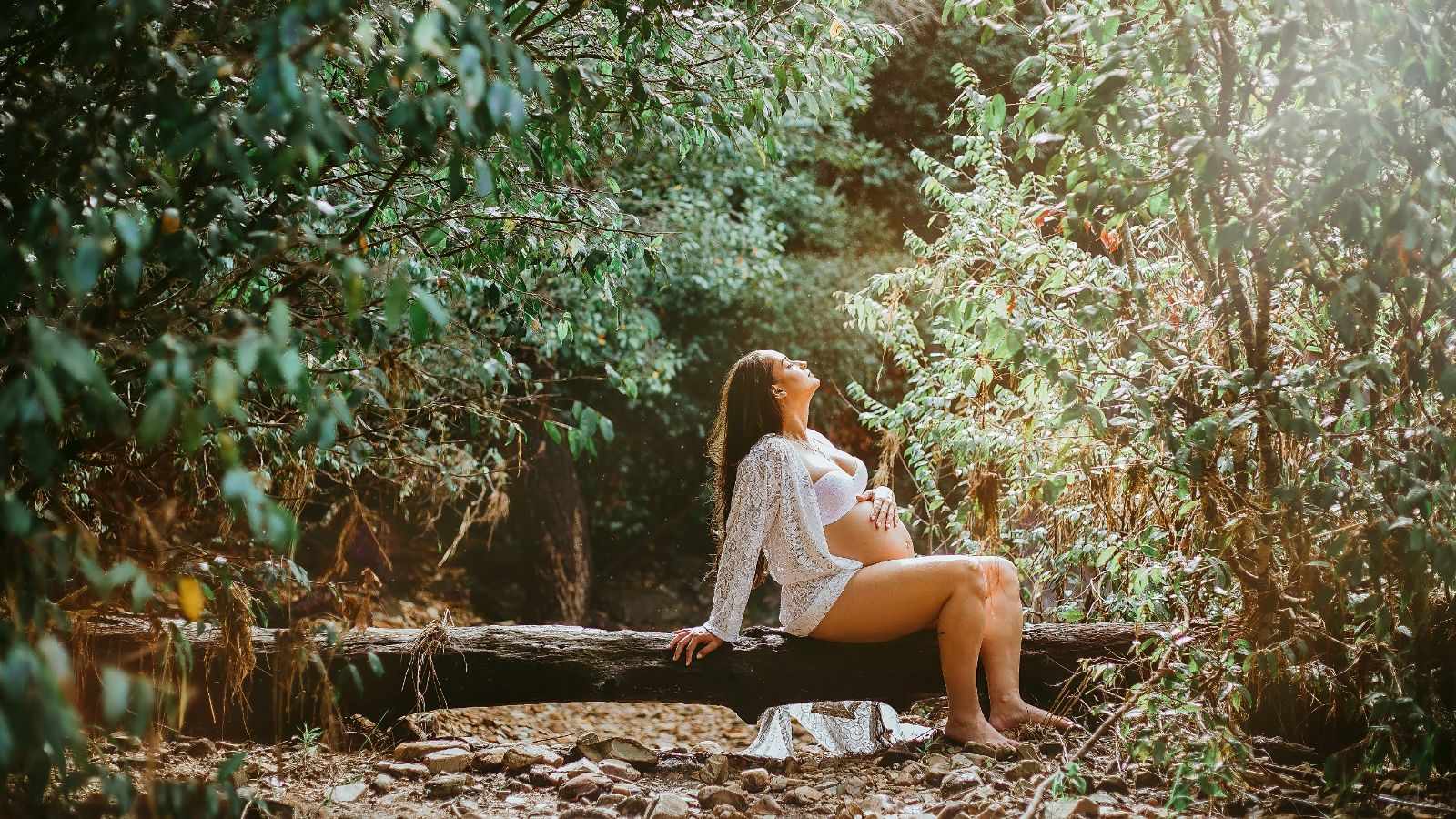 A pregnant woman sunbathes in the forest.