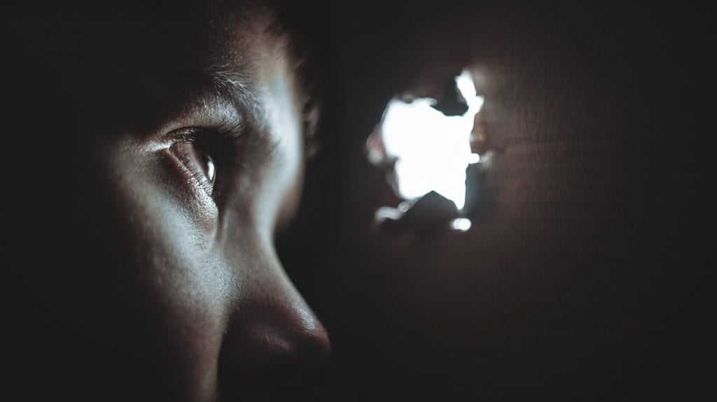 A child peeks through a hole in the wall