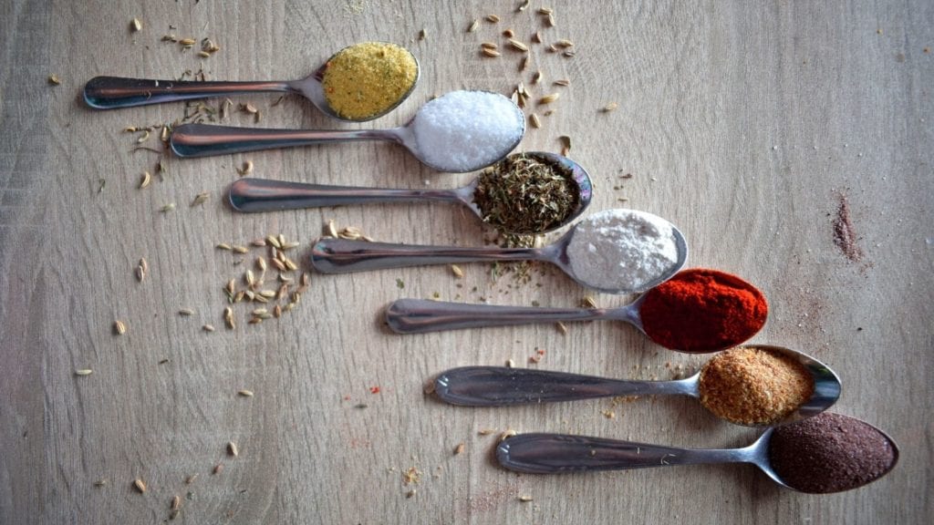 Spoons displayed full of colourful and aromatic herbs.