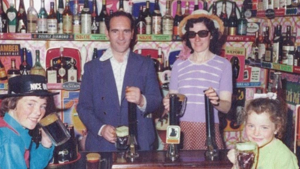 A family including small children at a bar drinking beer together.