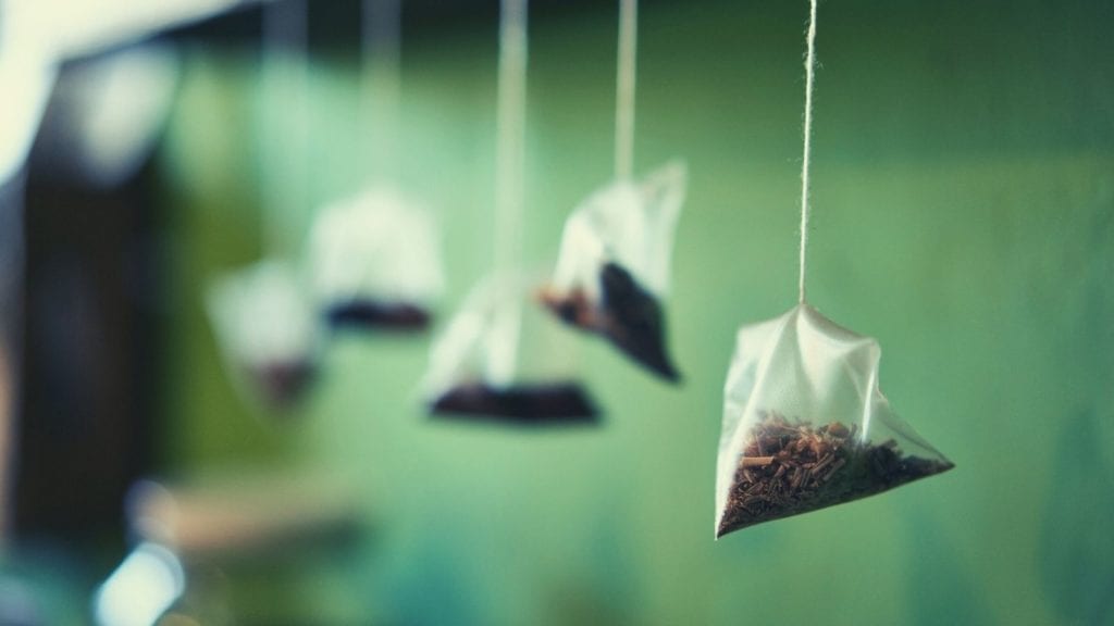 Tea bags full of herbal tea hanging in a row.