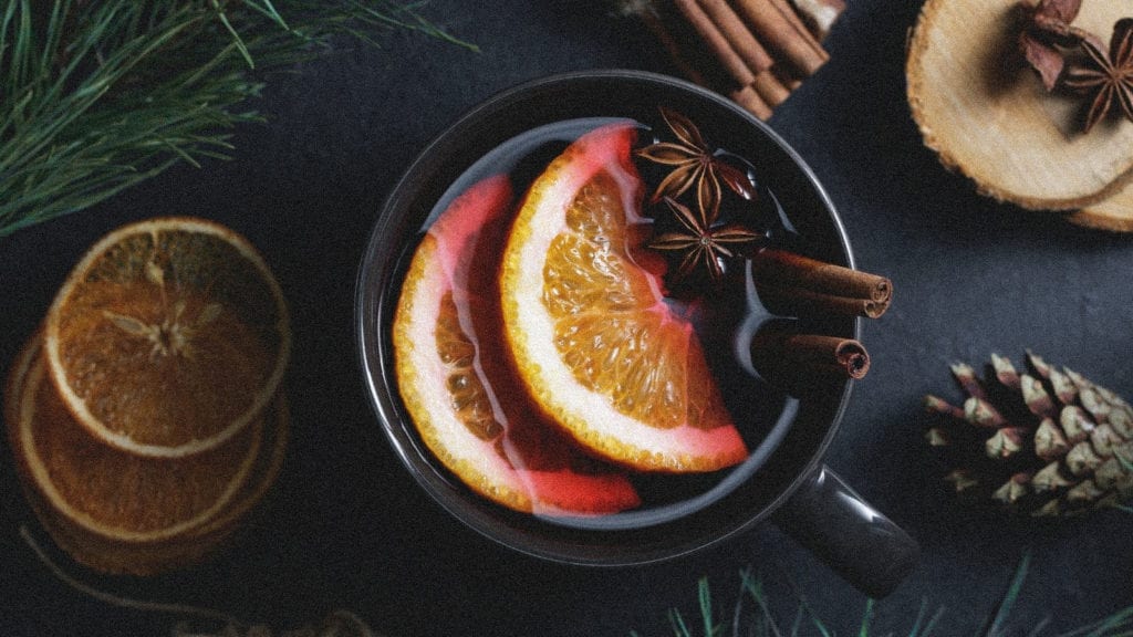 A mug of mulled wine filled with oranges, star anise and cinnamon.