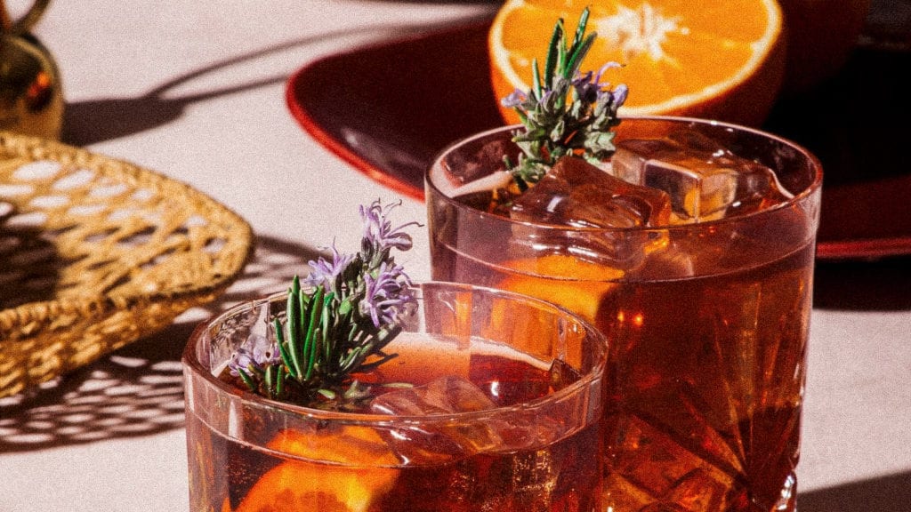 Two cups of negroni decorated with rosemary flowers