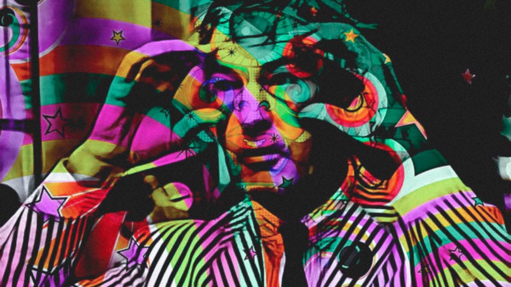 A psychedelic, artistic photograph of Timothy Leary holding imaginary binoculars up to his head.
