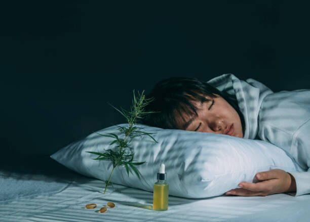 Woman fast asleep after using a cannabis tincture for sleep. There is a cannabis plant leaning against her pillow