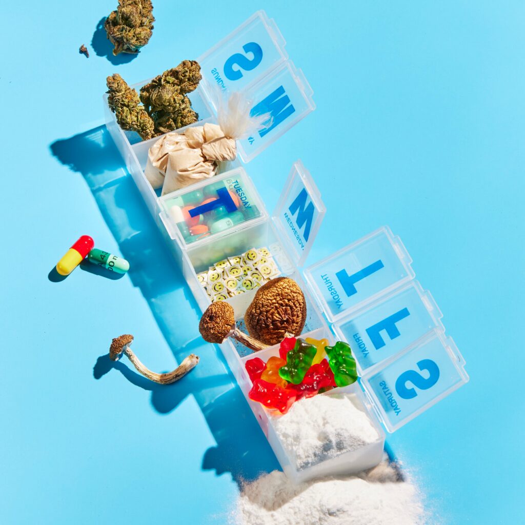 Image of capsule organizer with cannabis flower, lsd, psilocybin mushrooms, and other drugs and pharmaceuticals for a guide to choosing a magic mushroom strain