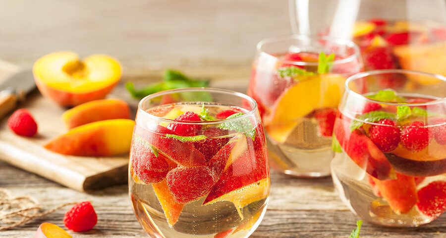 Photograph of a green tea sangria filled with raspberries, peaches, and mint leaves for an article on cannabis mocktail recipes